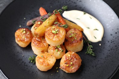 Photo of Delicious fried scallops with carrot and spices on dark gray plate, closeup