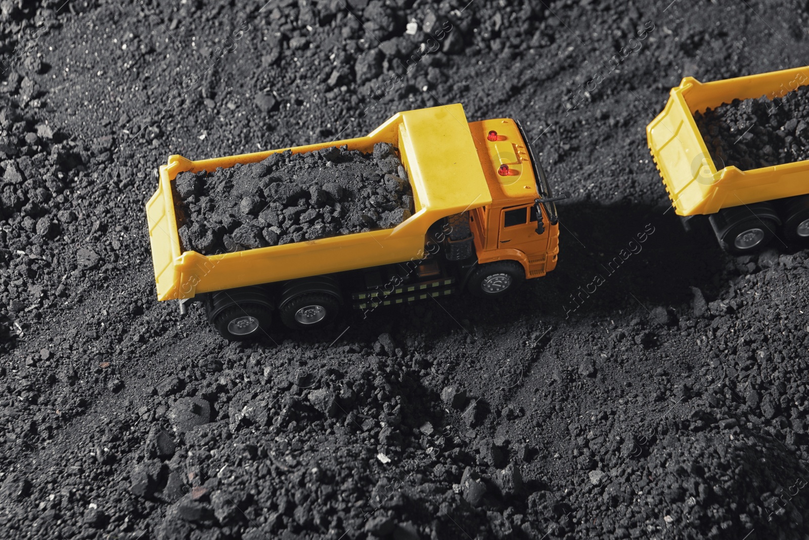 Image of Toy tipper trucks with coal in field