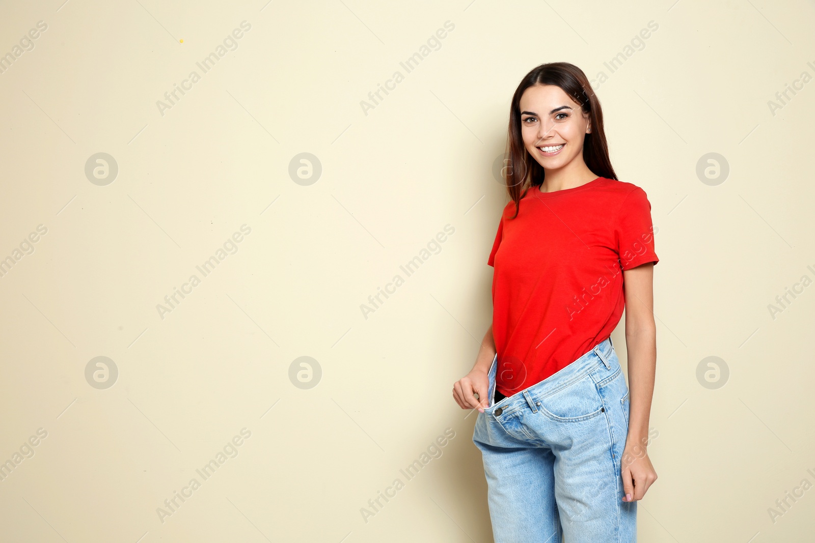 Photo of Slim woman in oversized jeans on color background, space for text. Weight loss