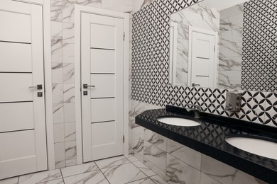 Photo of Public toilet interior with stylish white tiles