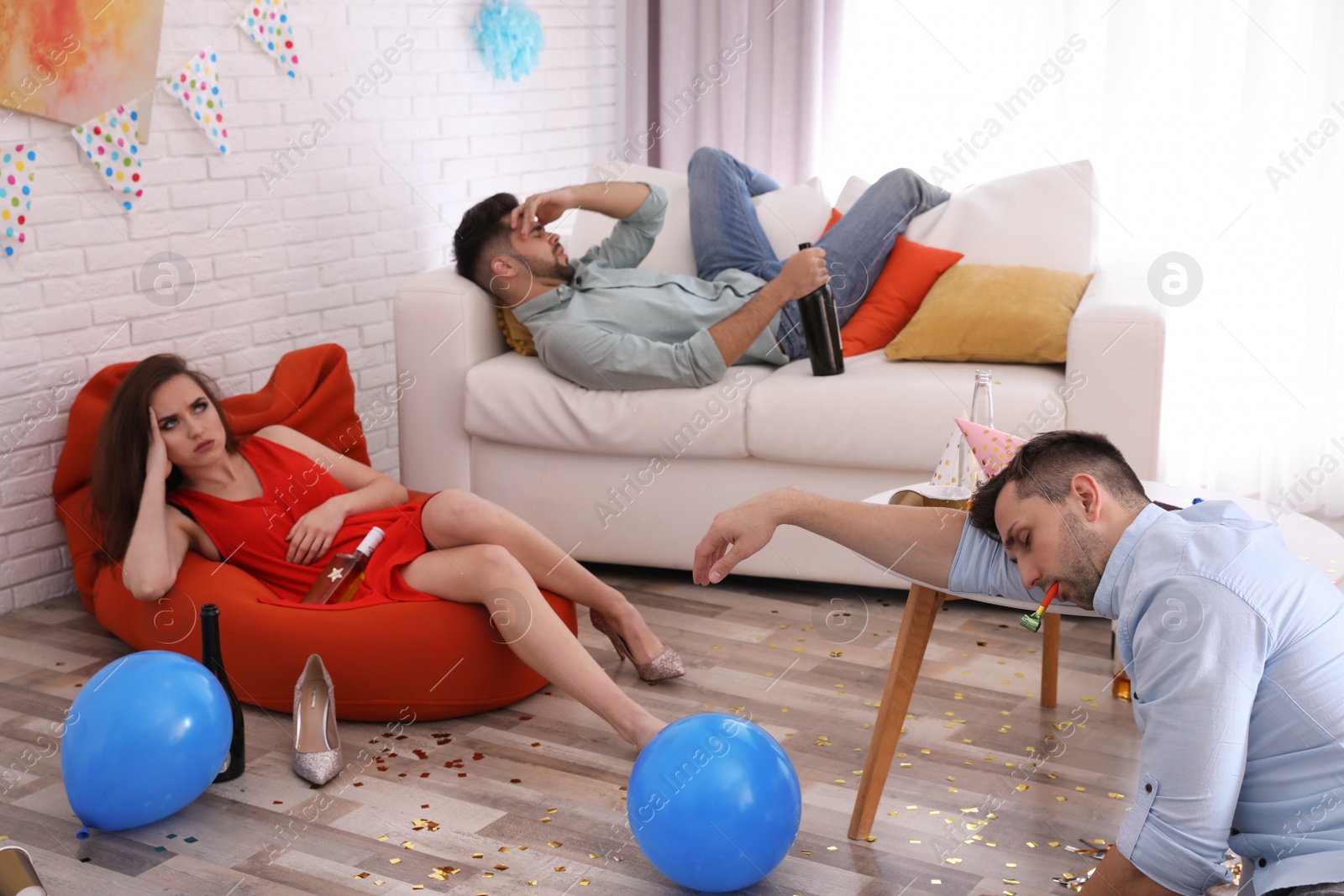 Photo of Friends suffering from hangover in messy room after party
