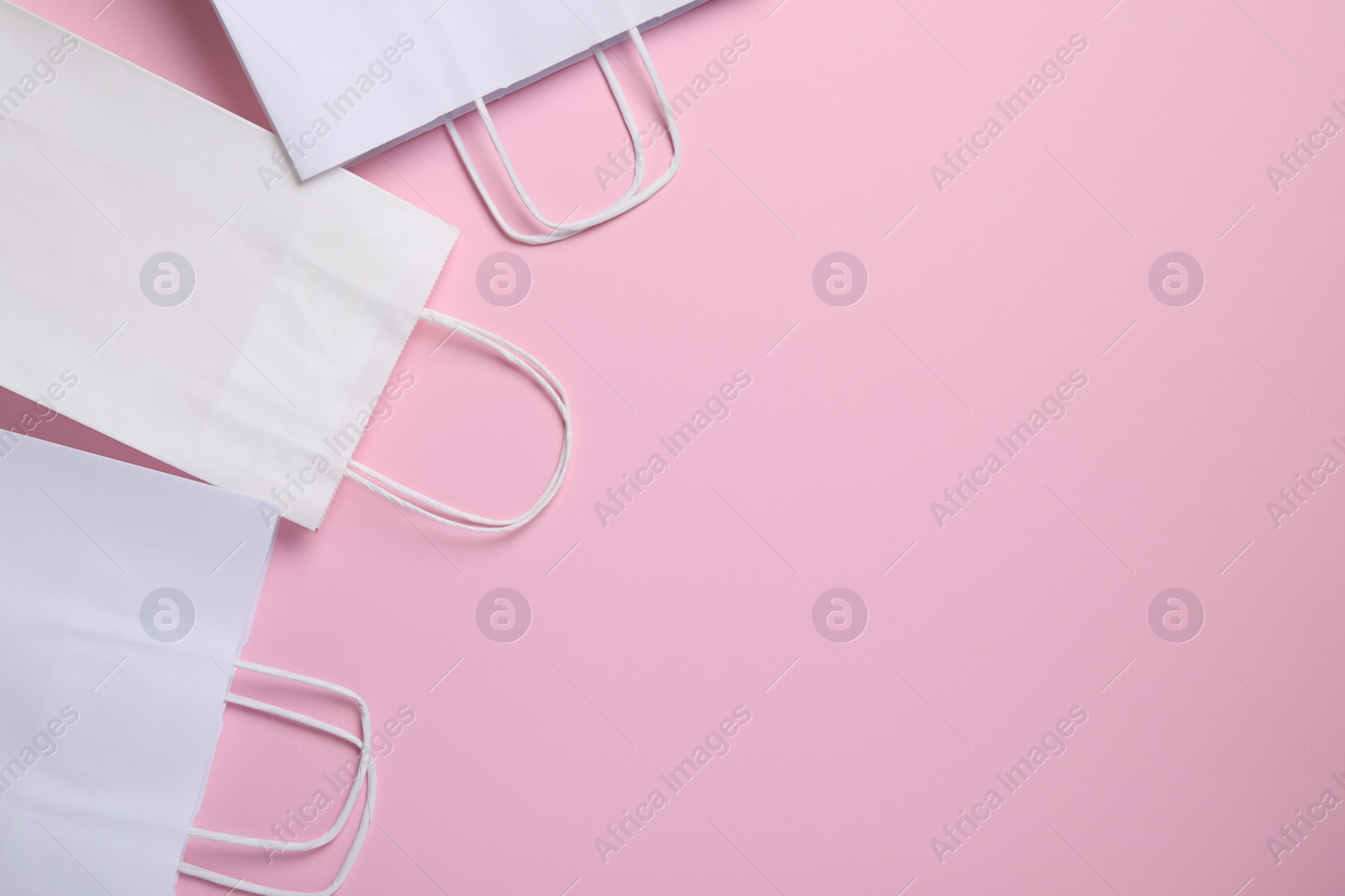 Photo of White paper bags on pink background, top view. Space for text