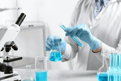 Scientist working with beaker and test tube in laboratory, closeup