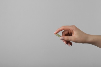 Photo of Woman holding vitamin capsule on grey background, closeup with space for text. Health supplement