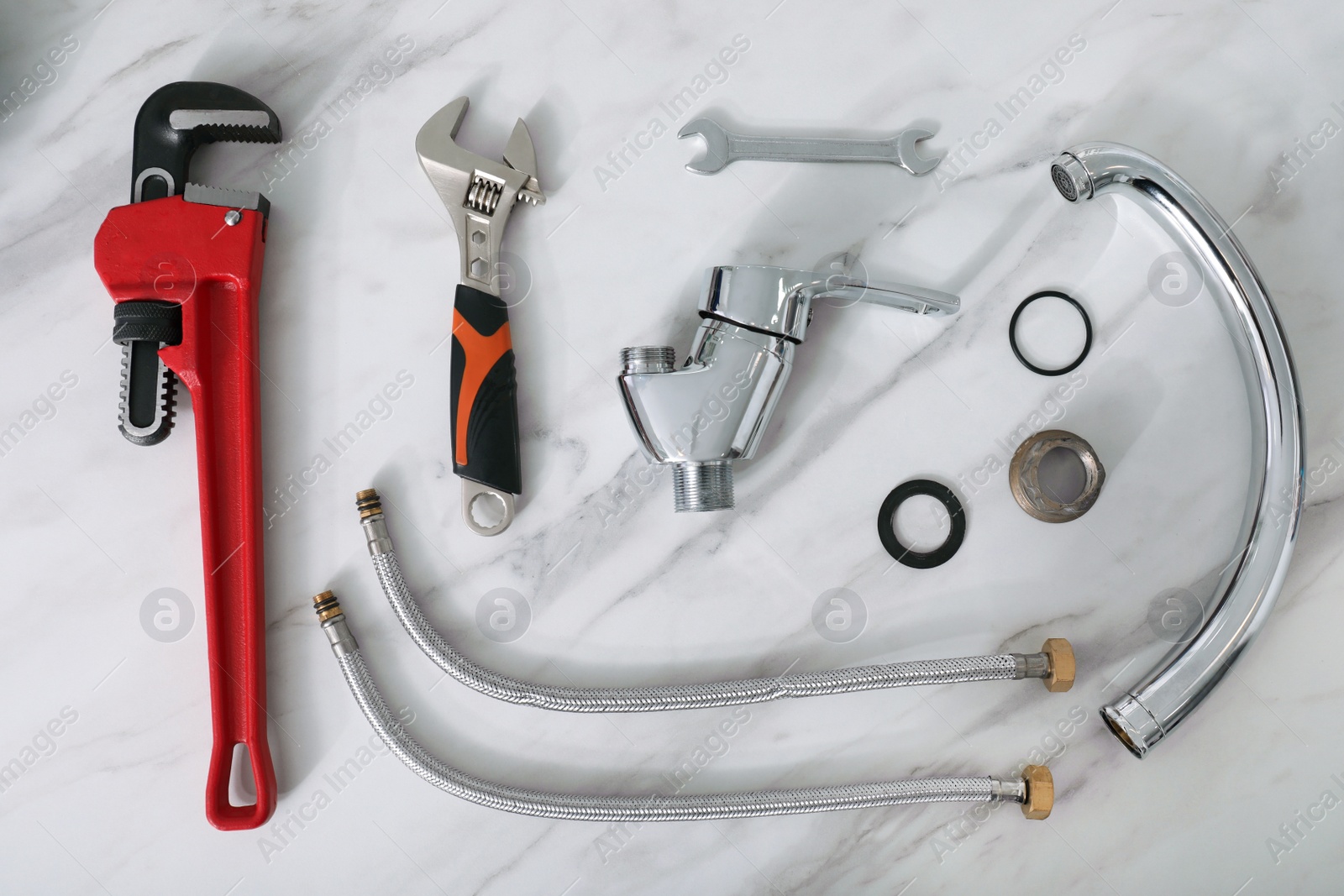 Photo of Parts of water tap and wrenches on white marble countertop, flat lay