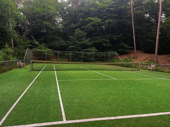 Tennis court with green grass and net outdoors