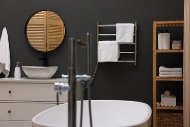 Photo of Stylish bathroom interior with heated towel rail and white tub