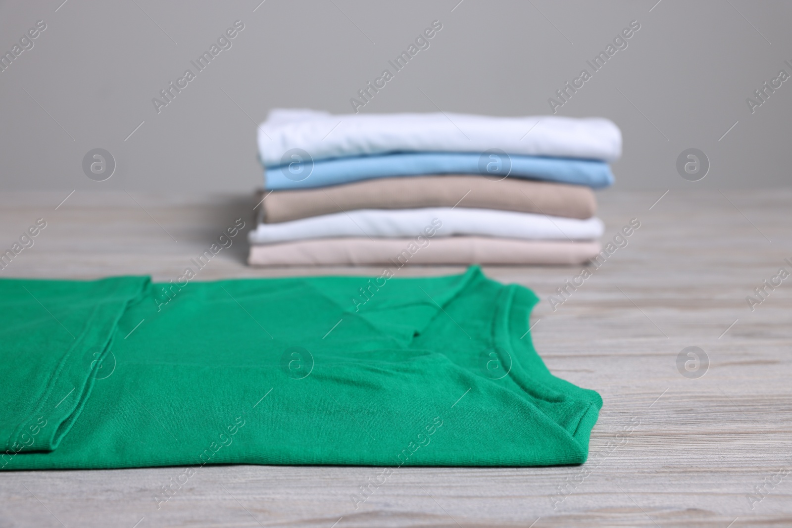 Photo of Sorting and organizing. Different folded and stacked clothes on light wooden table