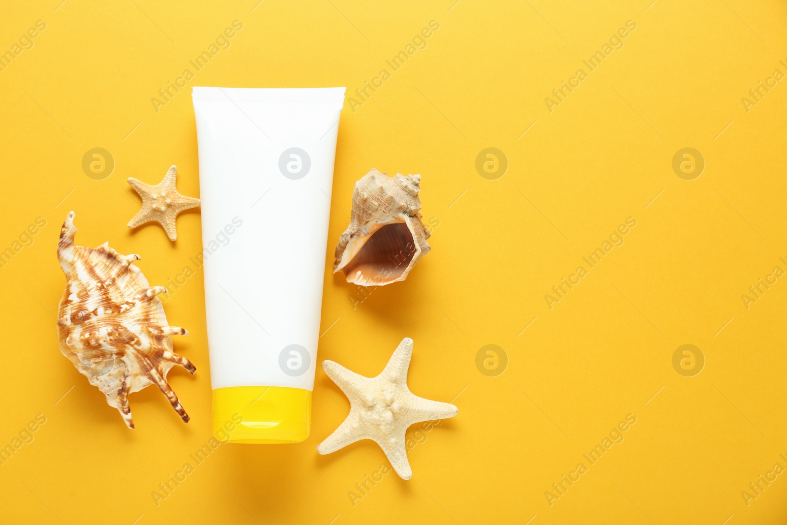 Photo of Suntan product, starfishes and seashells on orange background, flat lay. Space for text