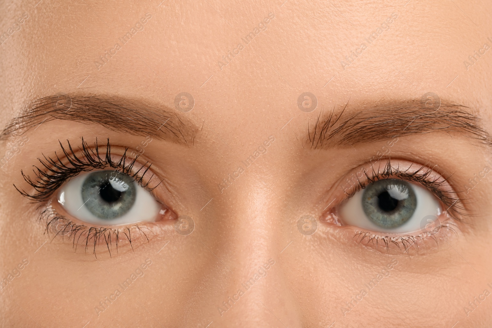 Photo of Woman showing difference in eyelashes length after mascara applying, closeup