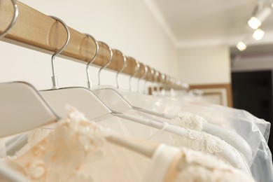 Different wedding dresses on hangers in boutique, closeup