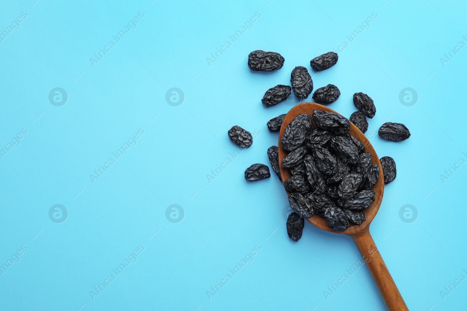 Photo of Spoon of raisins on color background, top view with space for text. Dried fruit as healthy snack