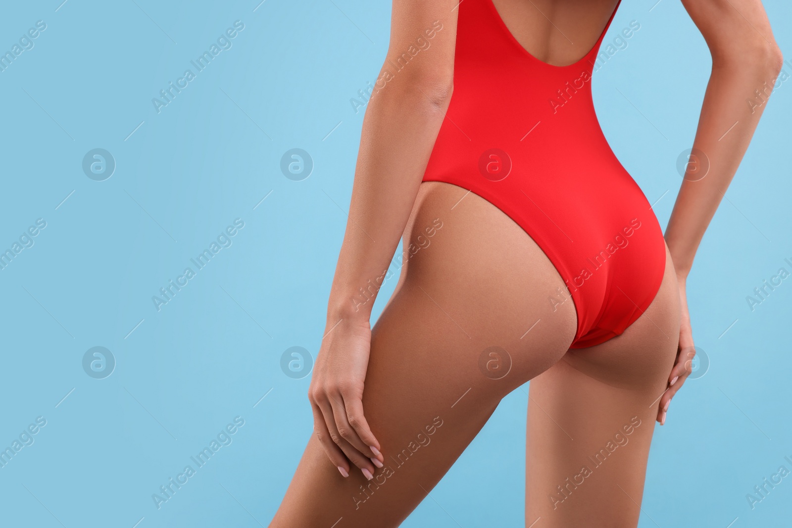 Photo of Young woman in stylish swimsuit on light blue background, closeup. Space for text