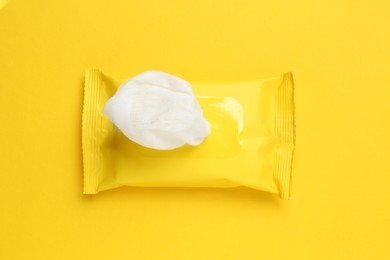 Photo of Wet wipes flow pack on yellow background, top view