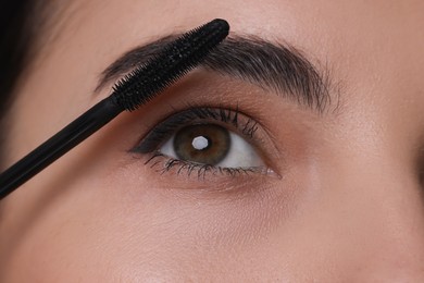 Photo of Beautiful young woman applying mascara, closeup view