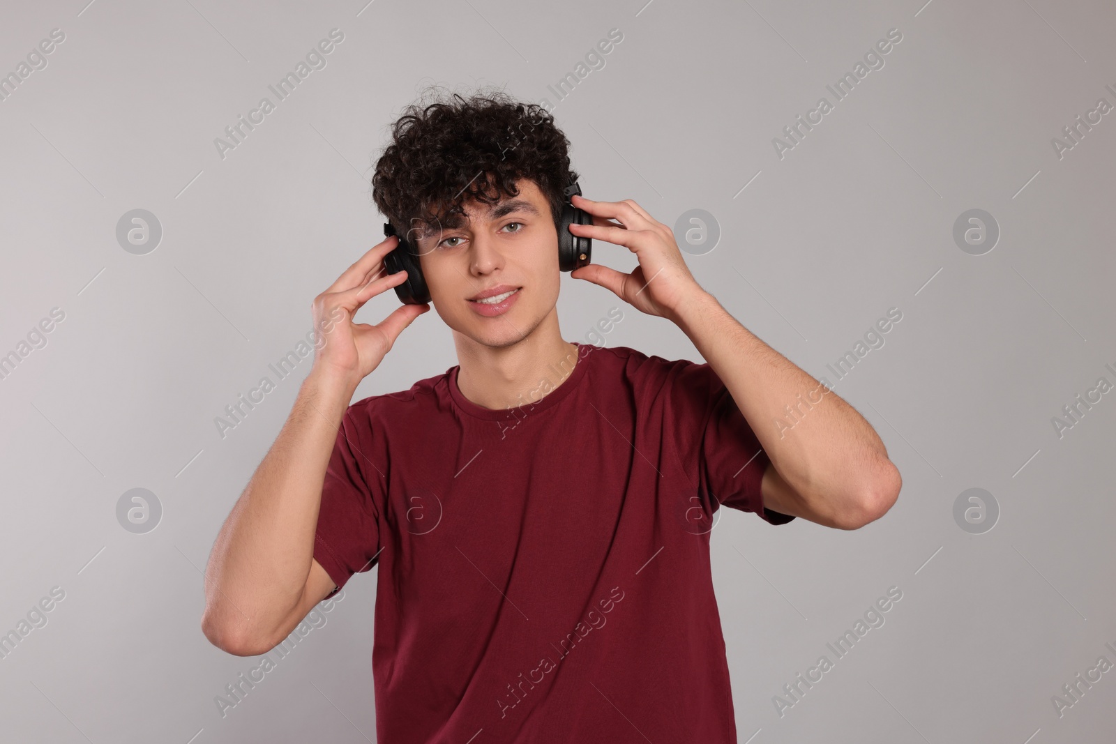 Photo of Handsome young man listening to music with headphones on light grey background