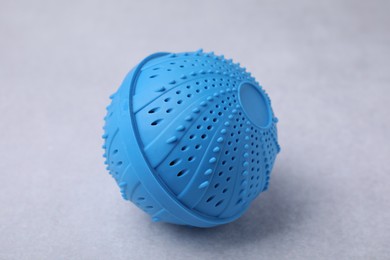 Photo of Blue dryer ball for washing machine on light grey table, closeup