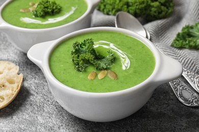 Photo of Tasty kale soup with pumpkin seeds on grey table, closeup
