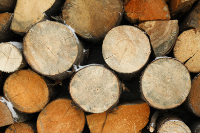 Photo of Stacked firewood with snow as background, closeup. Heating house in winter