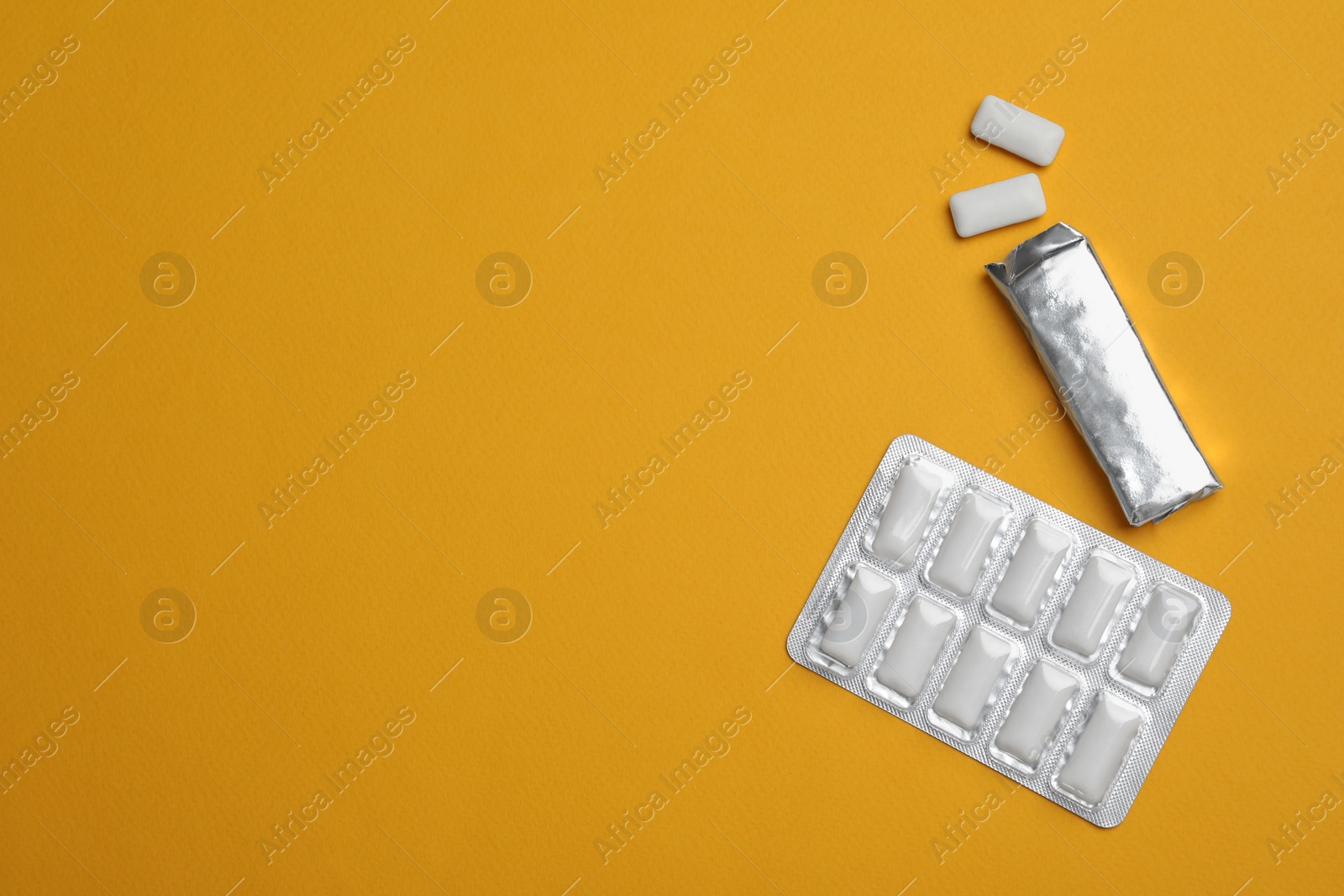 Photo of Packs with chewing gums on orange background, flat lay. Space for text