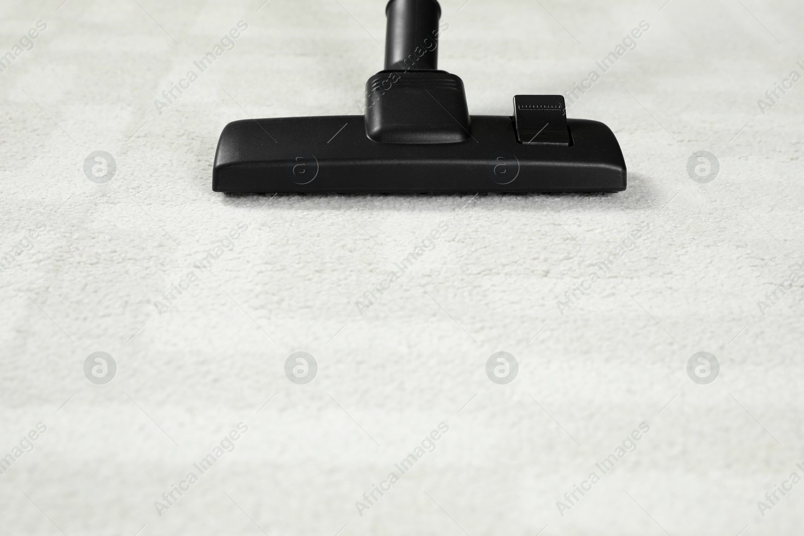 Photo of Removing dirt from white carpet with modern vacuum cleaner. Space for text