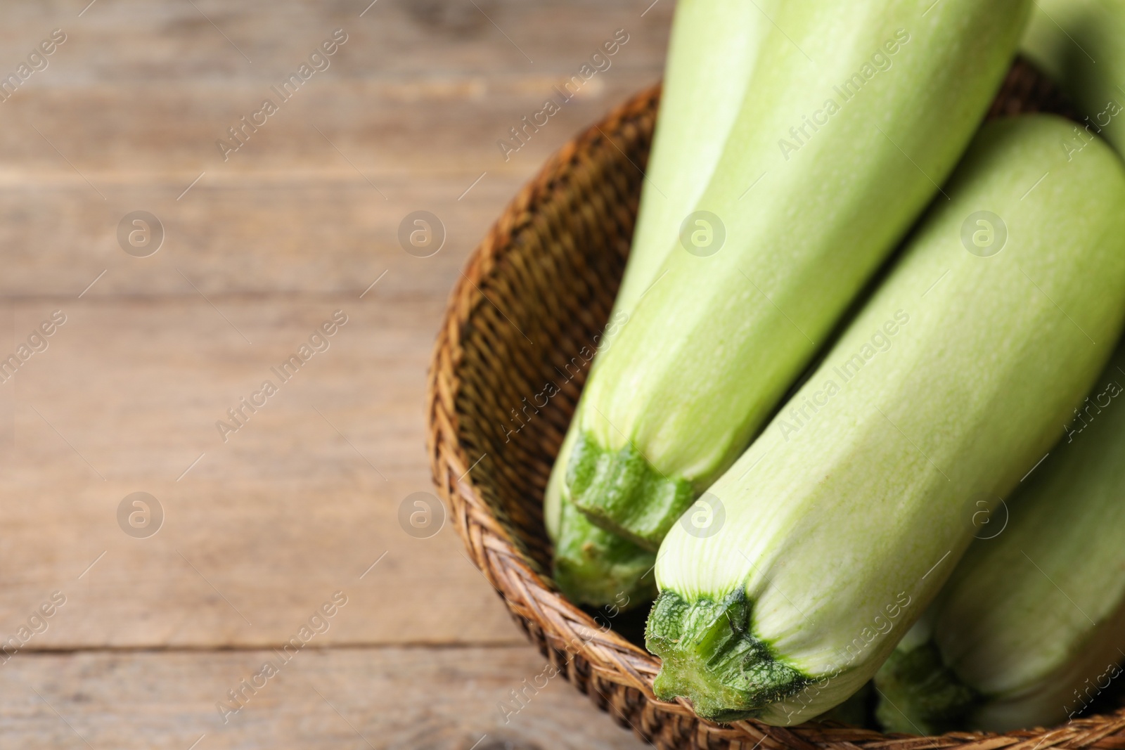 Photo of Ripe zucchinis on wooden table, closeup. Space for text