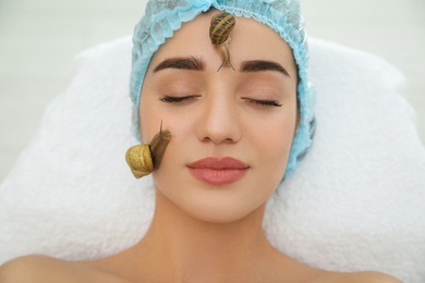 Young woman receiving snail facial massage in spa salon, closeup