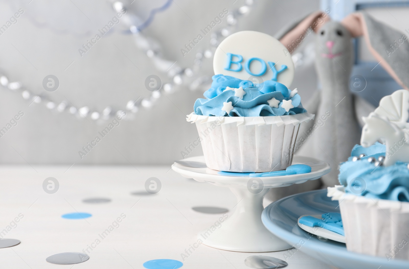 Photo of Delicious cupcake with light blue cream and Boy topper on white wooden table, space for text. Baby shower party