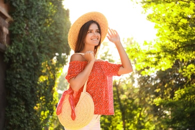 Young woman with stylish straw bag in park