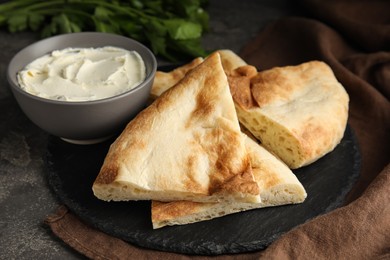 Cut pita bread, cream cheese and parsley on grey table, closeup