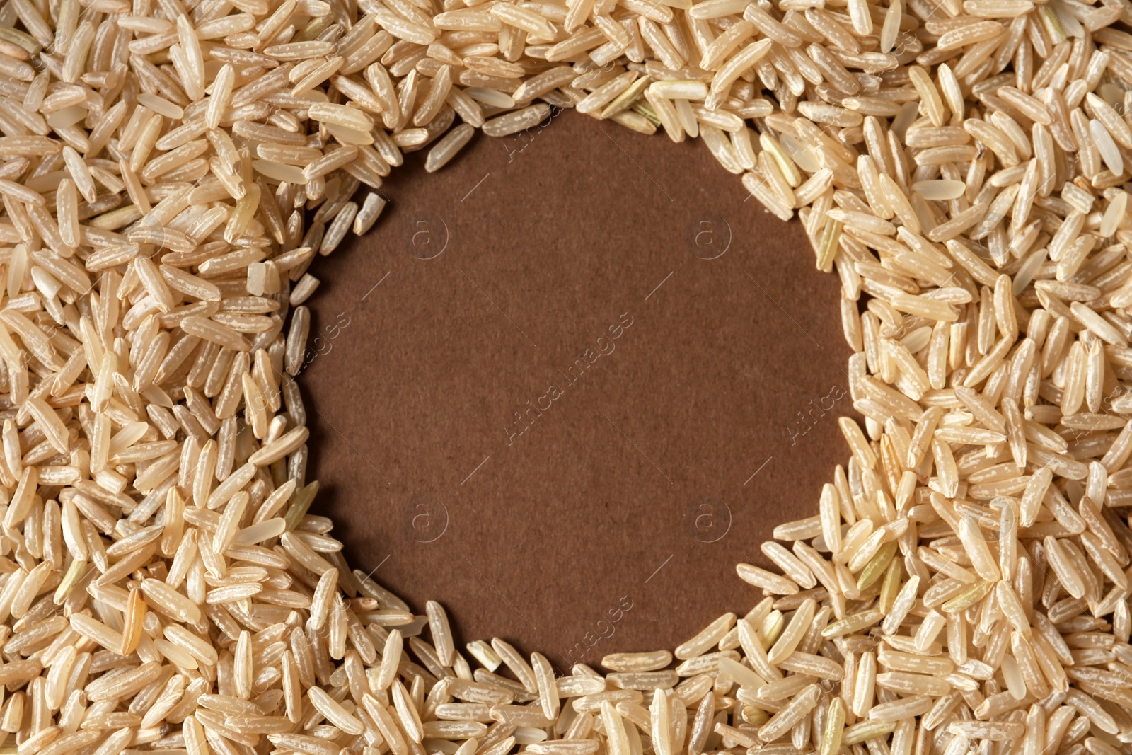 Photo of Round frame made with brown rice on color background. Space for text