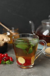 Photo of Glass cup of immunity boosting drink and ingredients on grey table