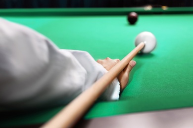 Young woman playing billiard indoors, closeup