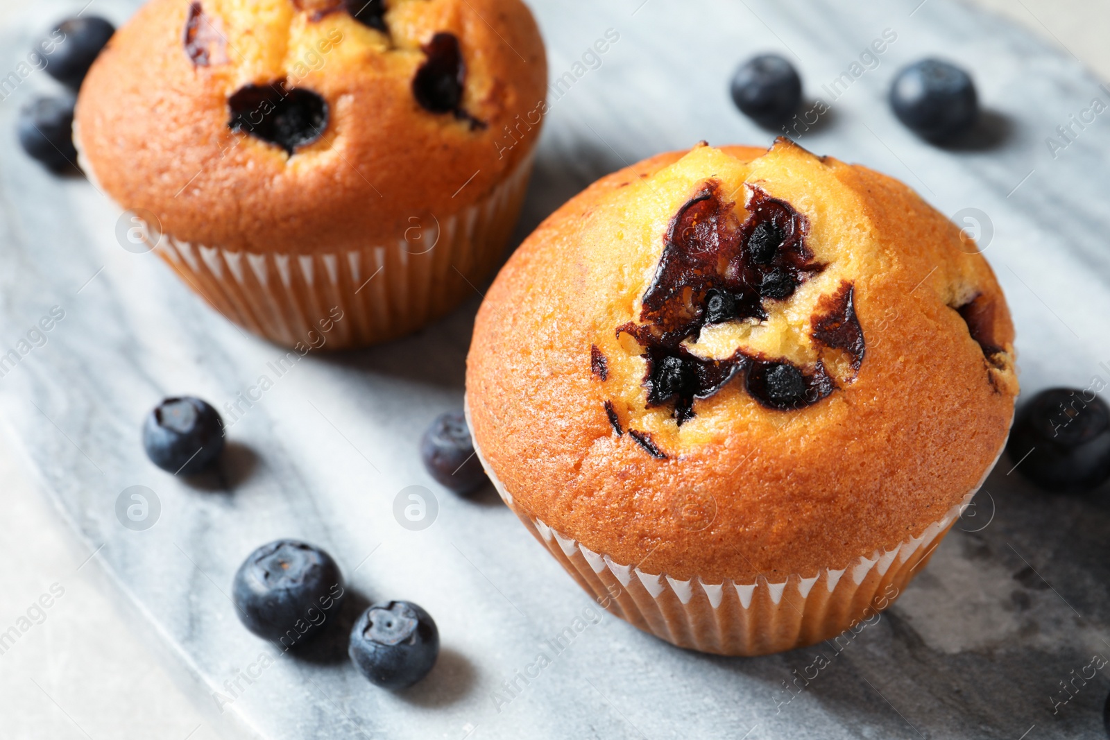 Photo of Muffins with blueberries on stone table, closeup view