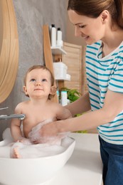 Photo of Mother washing her little baby in sink at home