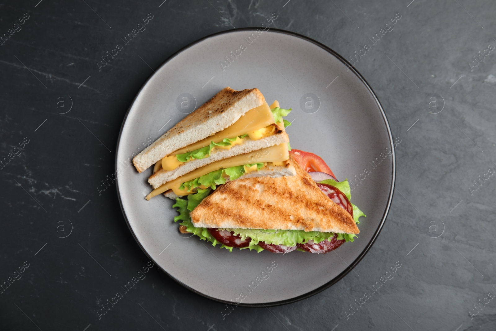 Photo of Plate with tasty sandwiches on black table, top view