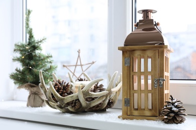 Photo of Beautiful Christmas lantern and other decorations on window sill