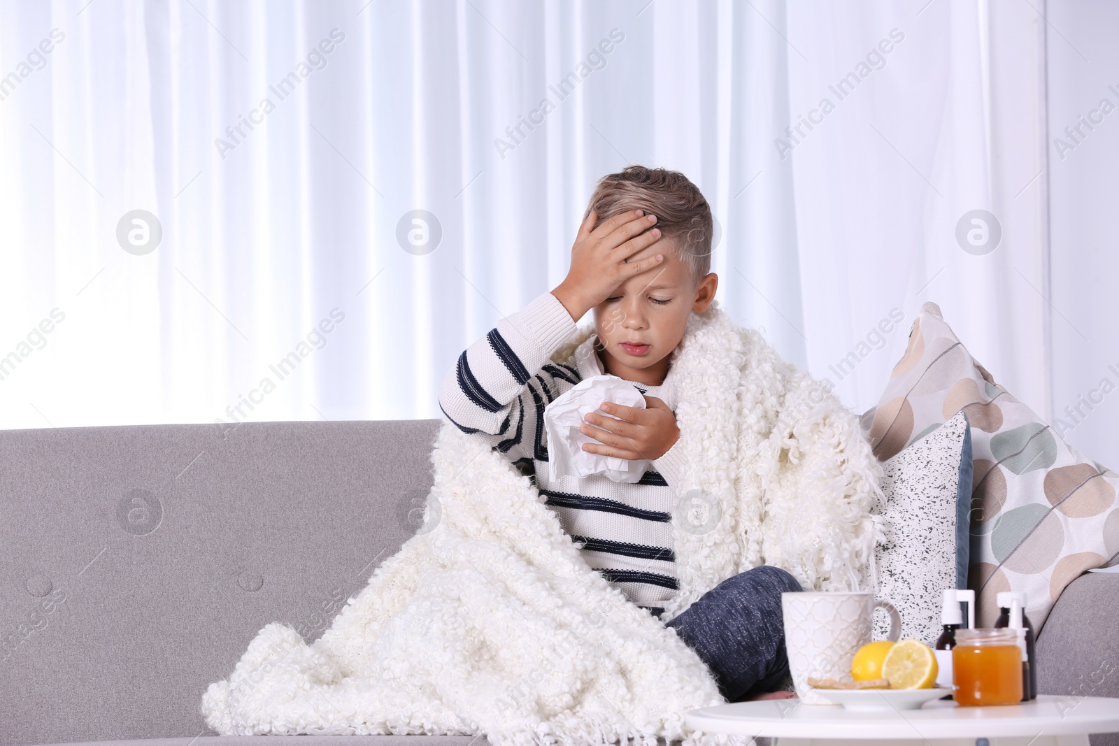 Photo of Ill boy suffering from cough on sofa at home