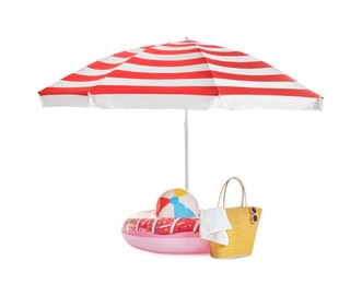 Photo of Open striped beach umbrella, inflatable toys, bag and accessories on white background