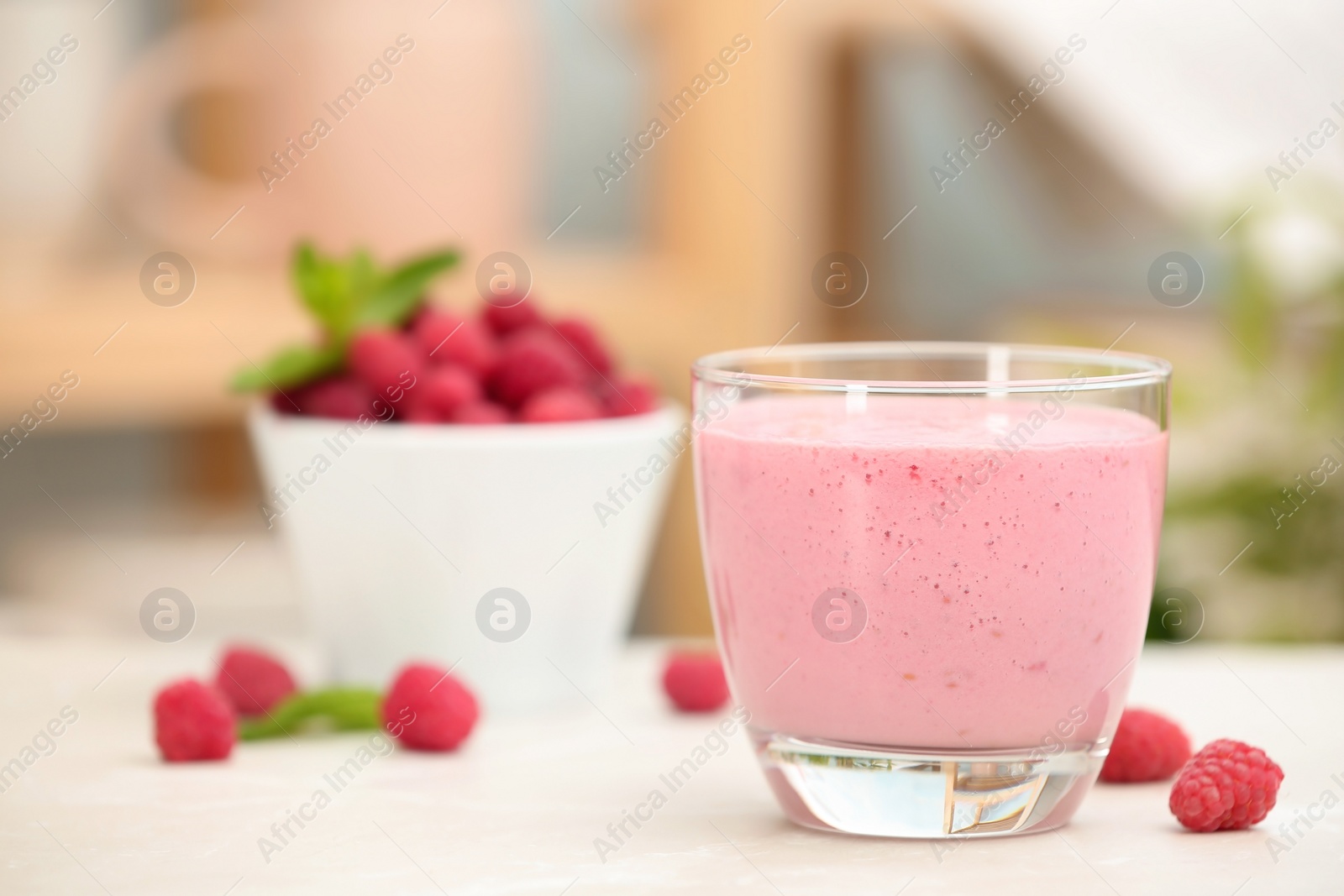 Photo of Delicious smoothie in glass and raspberries on table