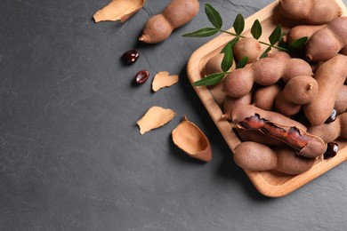 Photo of Delicious ripe tamarinds on black table, flat lay. Space for text