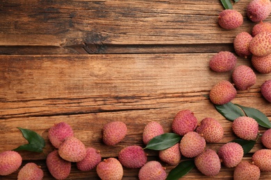 Photo of Fresh ripe lychee fruits on wooden table, flat lay. Space for text