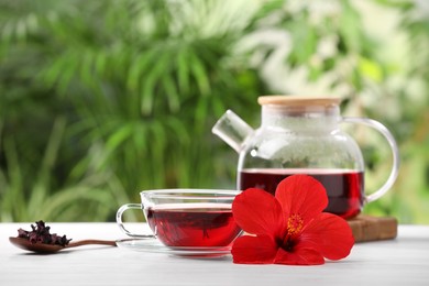 Delicious hibiscus tea and flowers on white wooden table outdoors, space for text