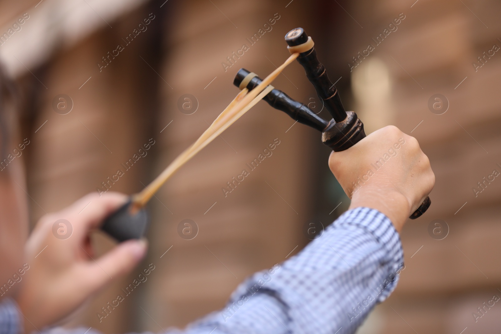 Photo of Little boy playing with slingshot outdoors, closeup