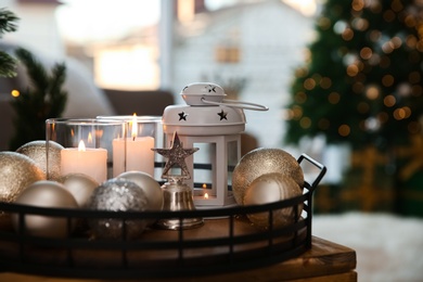 Burning candles, lantern and Christmas balls on wooden table indoors, closeup