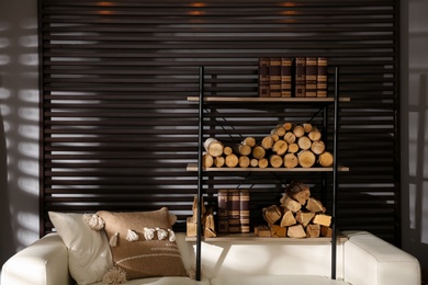 Photo of Shelving unit with stacked firewood and books near wall in room. Idea for interior design