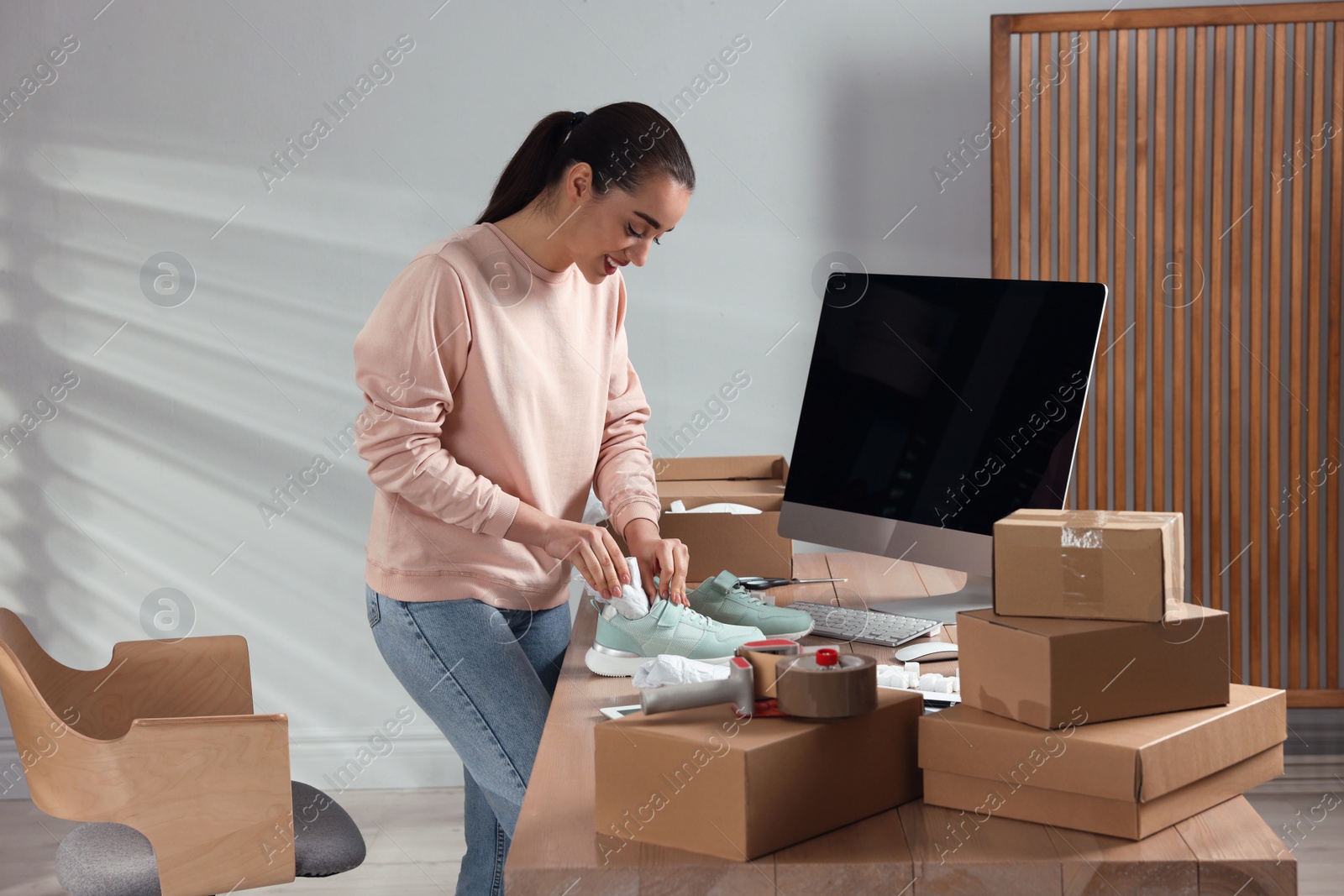 Photo of Seller packing shoes at workplace. Online store