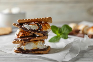 Delicious marshmallow sandwich with cracker and chocolate on white wooden table, closeup. Space for text