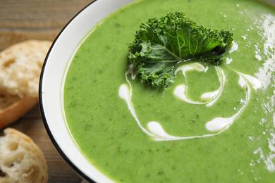 Photo of Tasty kale soup with cream on wooden table, closeup