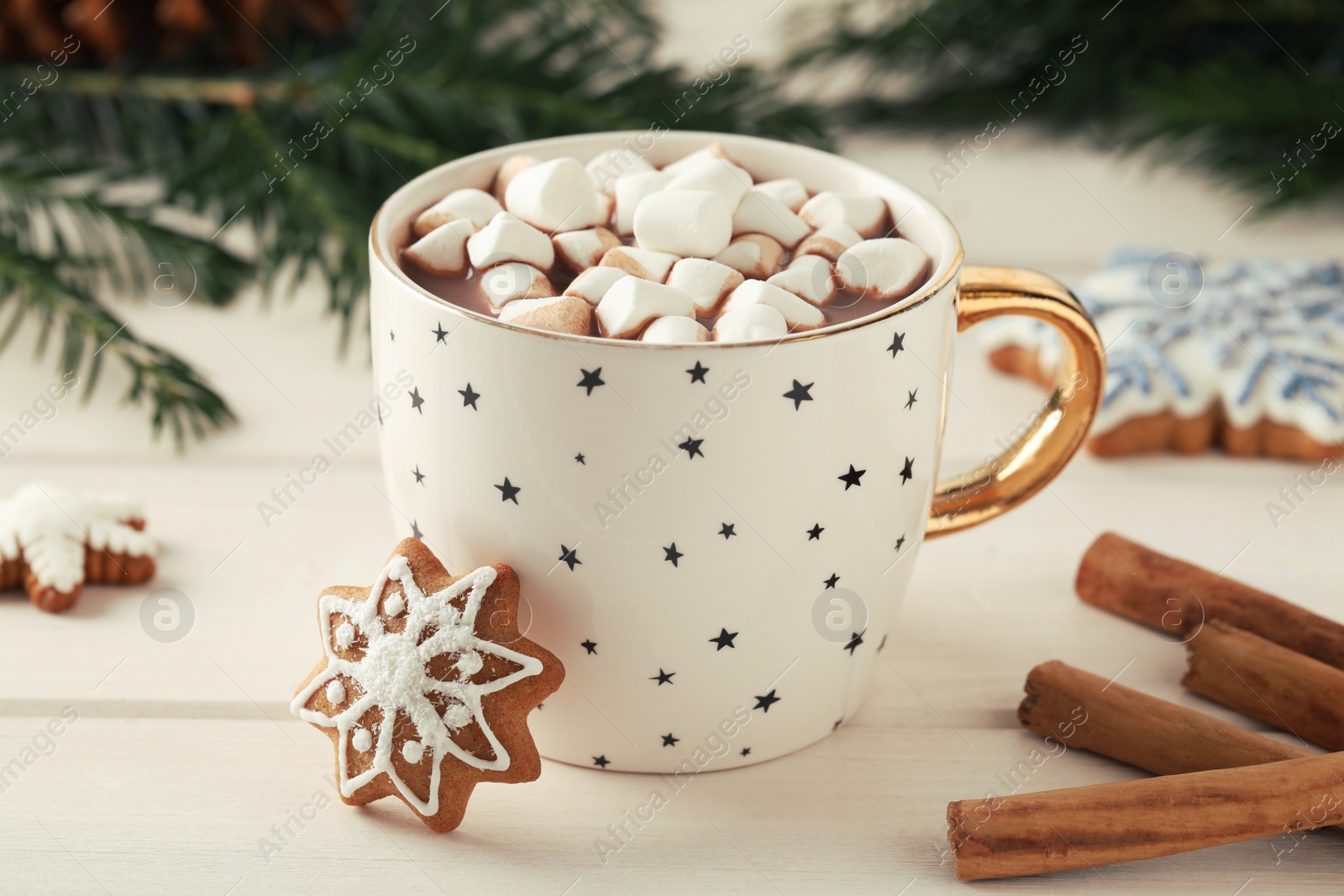 Photo of Delicious hot chocolate with marshmallows, gingerbread cookies and cinnamon on white wooden table, closeup